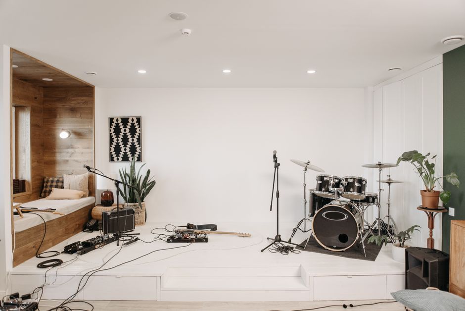 A modern music studio featuring a drum set, guitar, and cozy seating area for musicians.