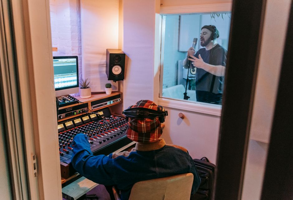 Musicians recording a song in a modern studio with audio engineer at mixing console.